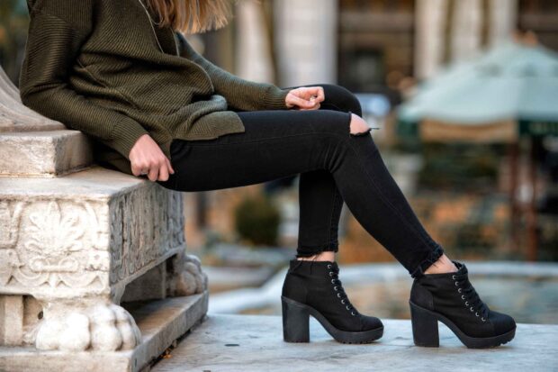 Woman wearing black high heels sitting on a stone bench outdoors