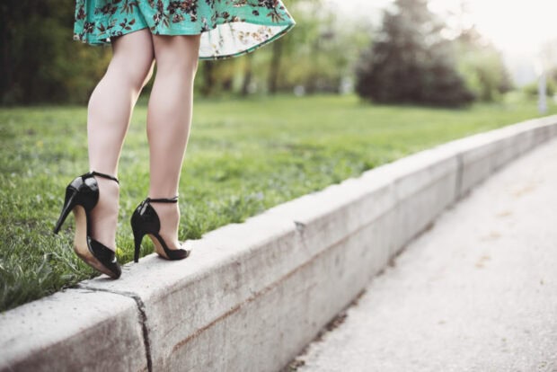Woman wearing high heels walking on a concrete curb outdoors