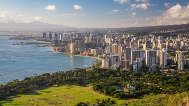 A panoramic view of Honolulu cityscape with lush green parks and blue ocean in Honolulu