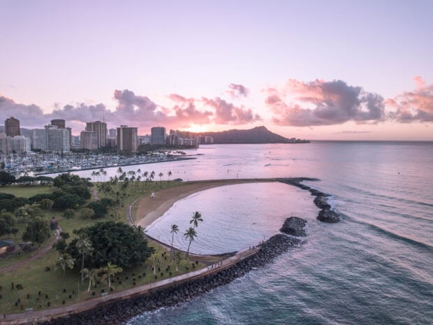 Aerial view of Honolulu city with Diamond Head mountain and coastline at sunset showcasing Honolulu scenery