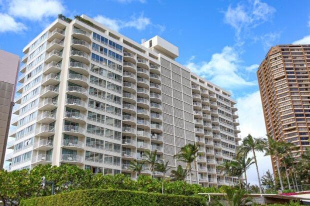 Modern apartment building in Honolulu with palm trees under a bright blue sky