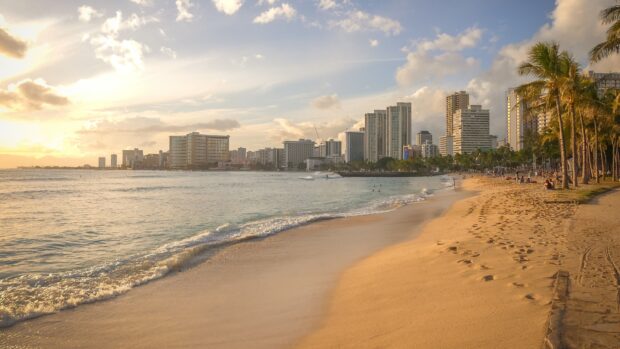 A beautiful Honolulu beach with golden sand and city skyline at sunset in Honolulu