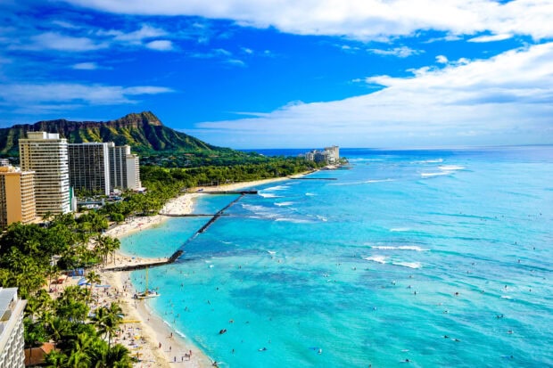 A vibrant Honolulu coastline with blue ocean and mountain landscape on a sunny day