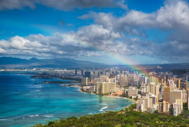A vibrant view of Honolulu cityscape with a rainbow over the coastline