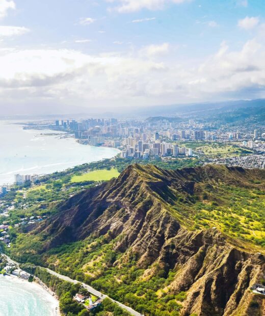 Aerial view of Honolulu cityscape with lush mountain ridges and coastline in Hawaii