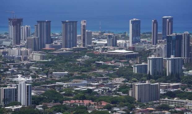 Aerial view of Honolulu cityscape with tall buildings and lush greenery in Honolulu