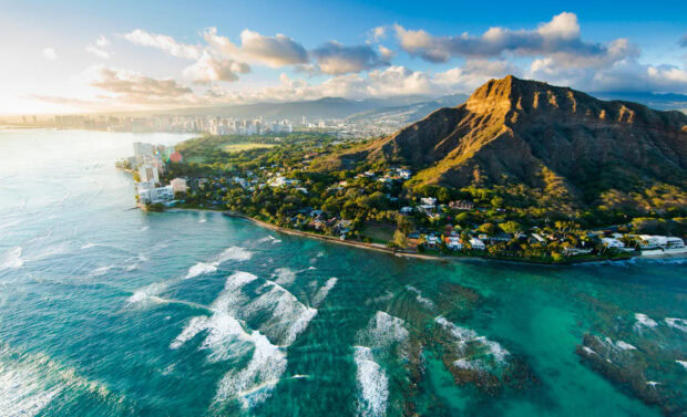 Aerial view of Honolulu coastline with Diamond Head mountain and clear blue ocean waves on a sunny day