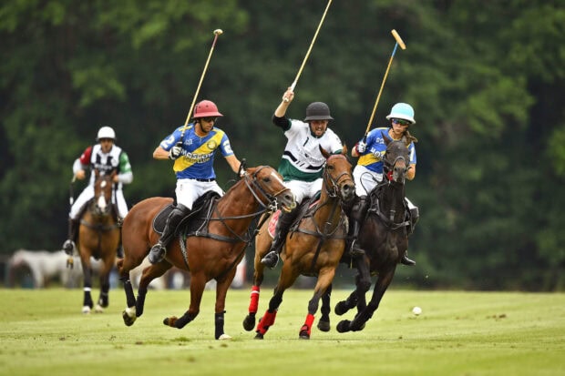 Three players competing in an intense horse polo match on a green field
