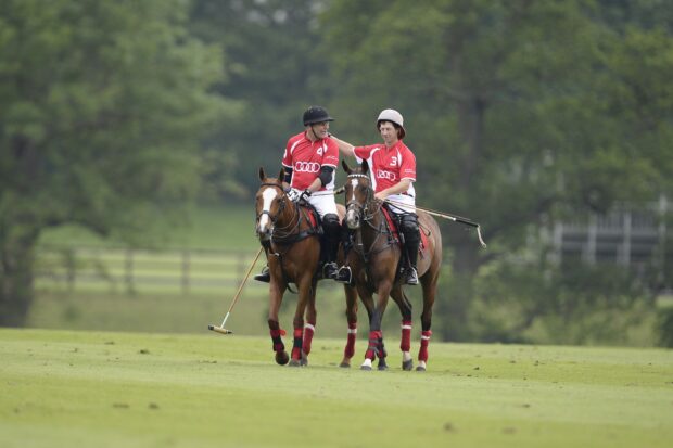 Two polo players riding horses during a horse polo match in green field