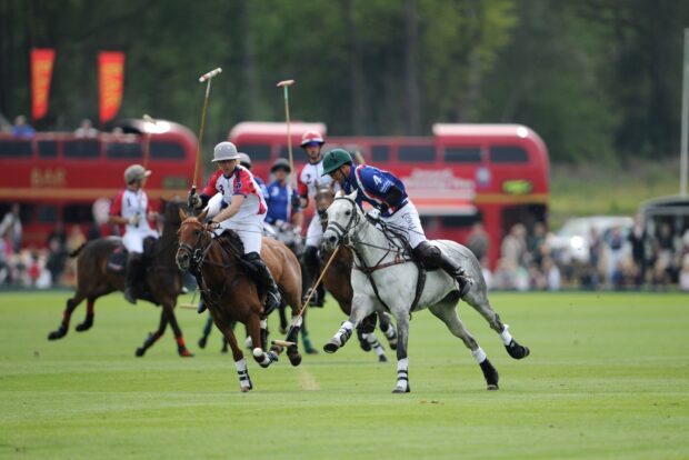 Two players compete in horse polo match riding horses on green field