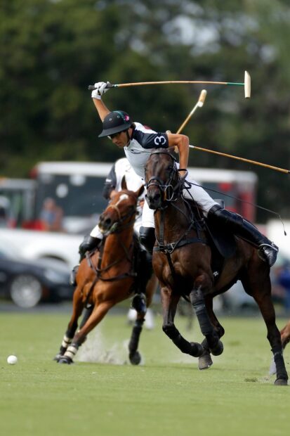 A polo player riding a horse striking the ball with a mallet during a horse polo match