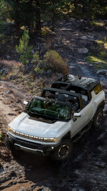 White rugged Hummer driving through muddy offroad trail with passengers inside