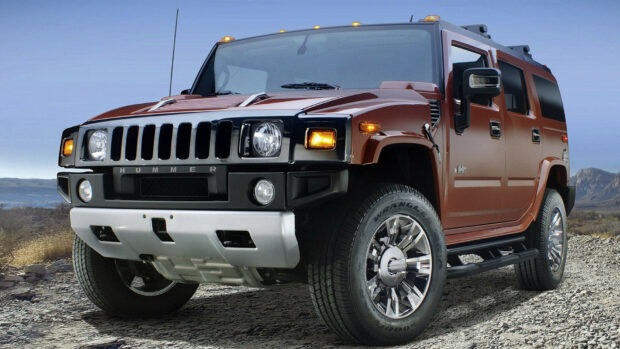 A rugged Hummer SUV parked on a rocky terrain under clear blue sky