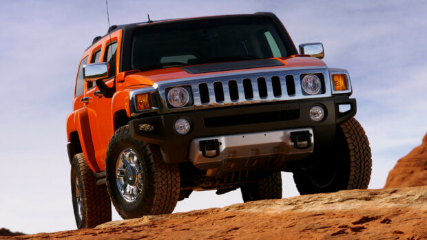 Orange Hummer standing on rocky terrain under clear sky