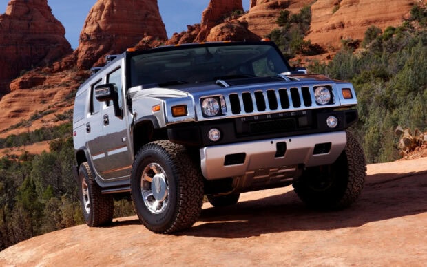 Silver Hummer vehicle driving on a rocky terrain in a desert environment