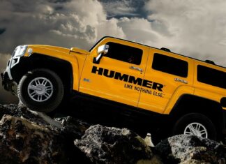 Yellow Hummer vehicle climbing rocky terrain under dramatic cloudy sky