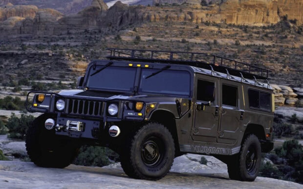 Black Hummer vehicle parked on rocky terrain in desert landscape