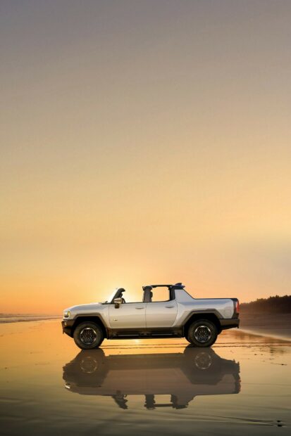 Silver Hummer with open roof parked on the beach during sunset