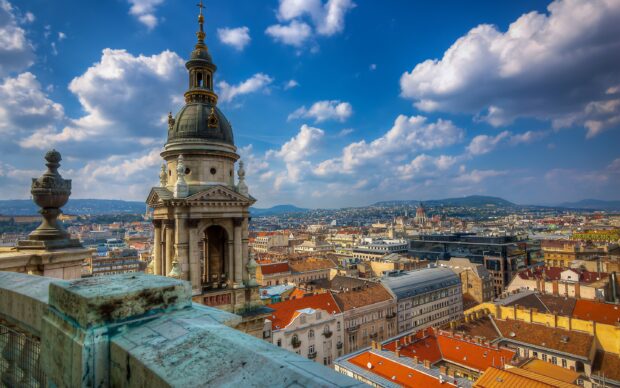 Historic bell tower and cityscape of Budapest Hungary under a blue sky with clouds