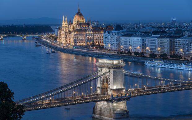 The Danube River and Chain Bridge illuminated at dusk in Budapest Hungary