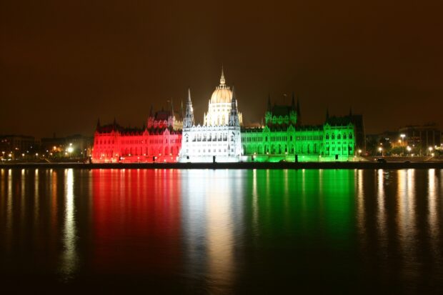 The illuminated parliament building with Hungarian colors reflecting on the river at night