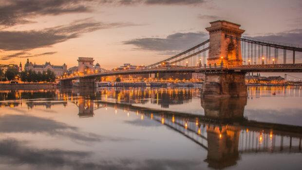 Chain Bridge in Budapest Hungary at sunset with city lights reflecting on the Danube river
