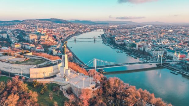 Aerial view of Hungary cityscape with river and statue on the hill at sunset