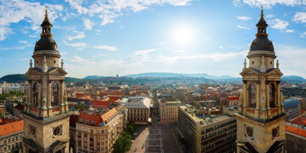 Historic towers overlooking a busy cityscape in Hungary during a bright sunny day