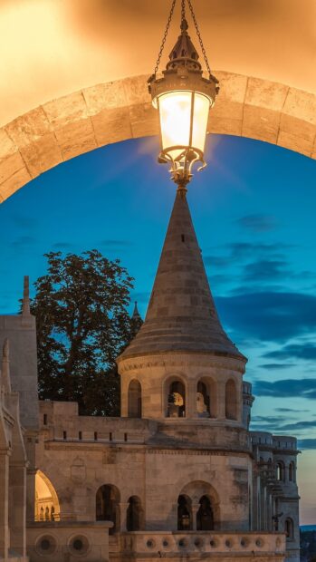 Historic tower in Hungary under glowing street lantern at dusk