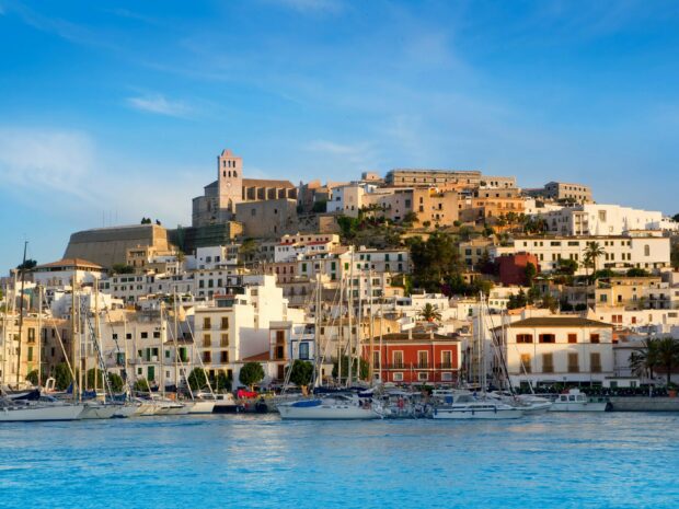 Historic Ibiza town with sailing boats by the water in a sunny day