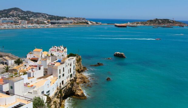 White mediterranean buildings on the coast of Ibiza surrounded by clear blue sea