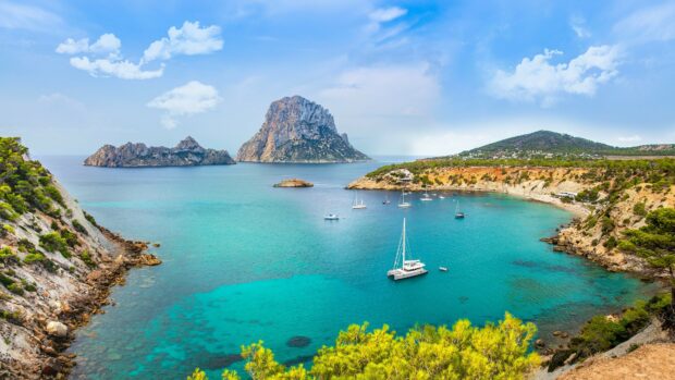 Crystal clear turquoise sea and rocky islands in Ibiza bay with sailing boats