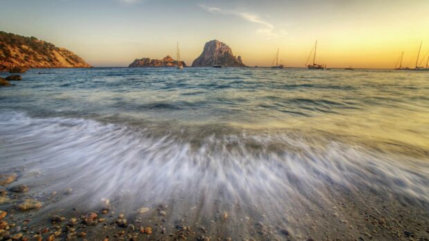 Calm Ibiza coast with clear water and rocky shore at sunset