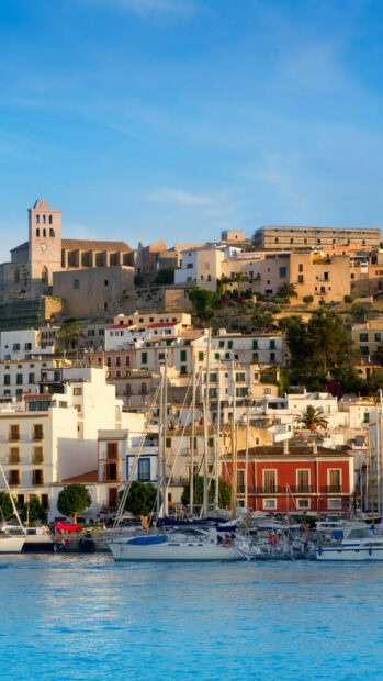 Scenic Ibiza town with colorful buildings and yachts docked in the harbor at sunset