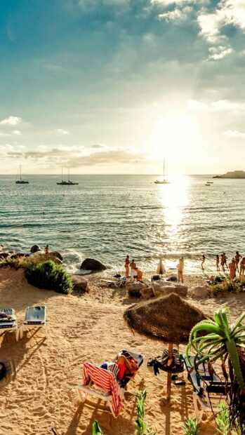 People enjoying the Ibiza coastline under the sun with boats in the sea