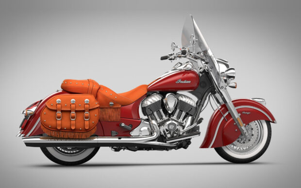 A classic Indian motorcycle with vintage design and leather saddlebags on a plain background