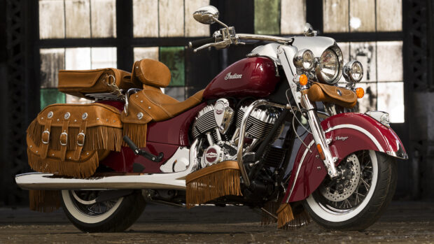 A vintage Indian motorcycle with leather saddlebags and fringe detailing parked indoors