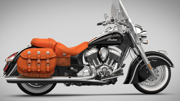 Classic Indian motorcycle with orange leather saddle and saddlebags on a grey background