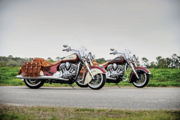 Two vintage Indian motorcycles parked on the roadside with leather saddlebags and chrome details