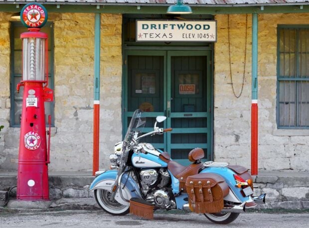 Vintage Indian motorcycle with leather saddlebags parked by an old gas station