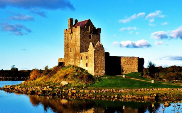 Historic Irish castle surrounded by water and green landscape on a sunny day