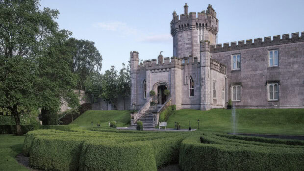 A historic Irish castle surrounded by manicured green hedges and lush trees