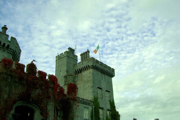 Ancient Irish castle with flag atop stone tower under cloudy sky