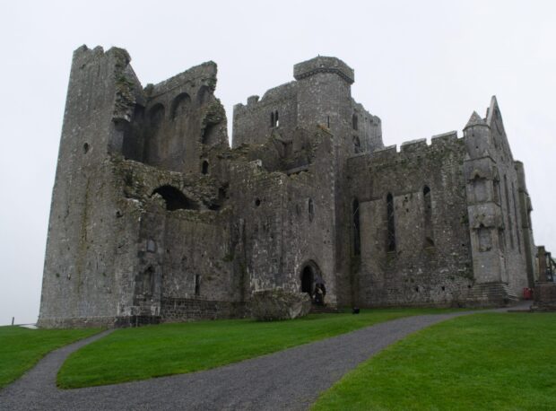 Ancient stone fortress ruins of Irish castle standing on green grass