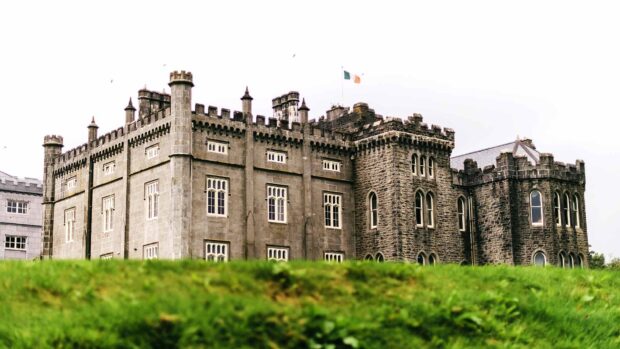 Historic castle in Ireland with stone towers and an Irish flag flying above the building