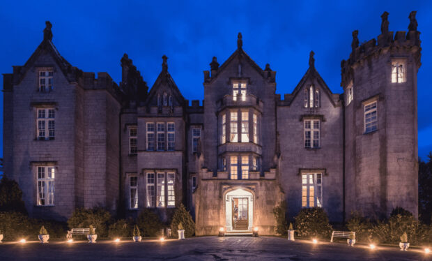 Historic Irish castle illuminated at night with glowing windows and stone architecture