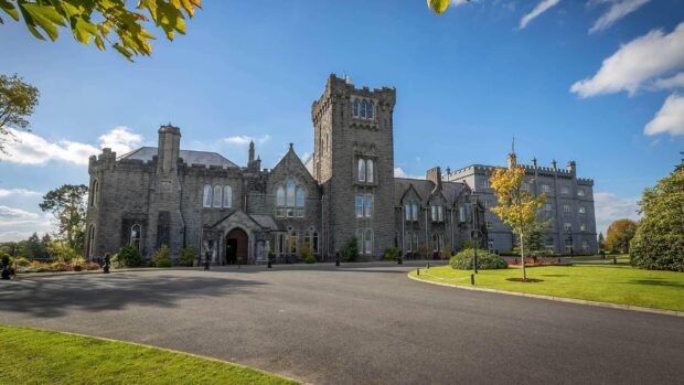 Historic Irish castle surrounded by greenery under a bright blue sky