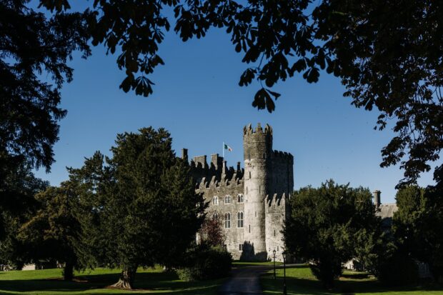 Historic Irish castle surrounded by lush green trees and blue sky in Ireland