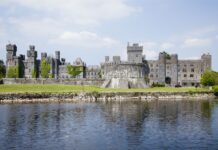 Historic stone Irish castle covered with ivy near calm water