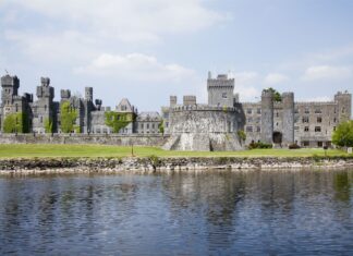 Historic stone Irish castle covered with ivy near calm water